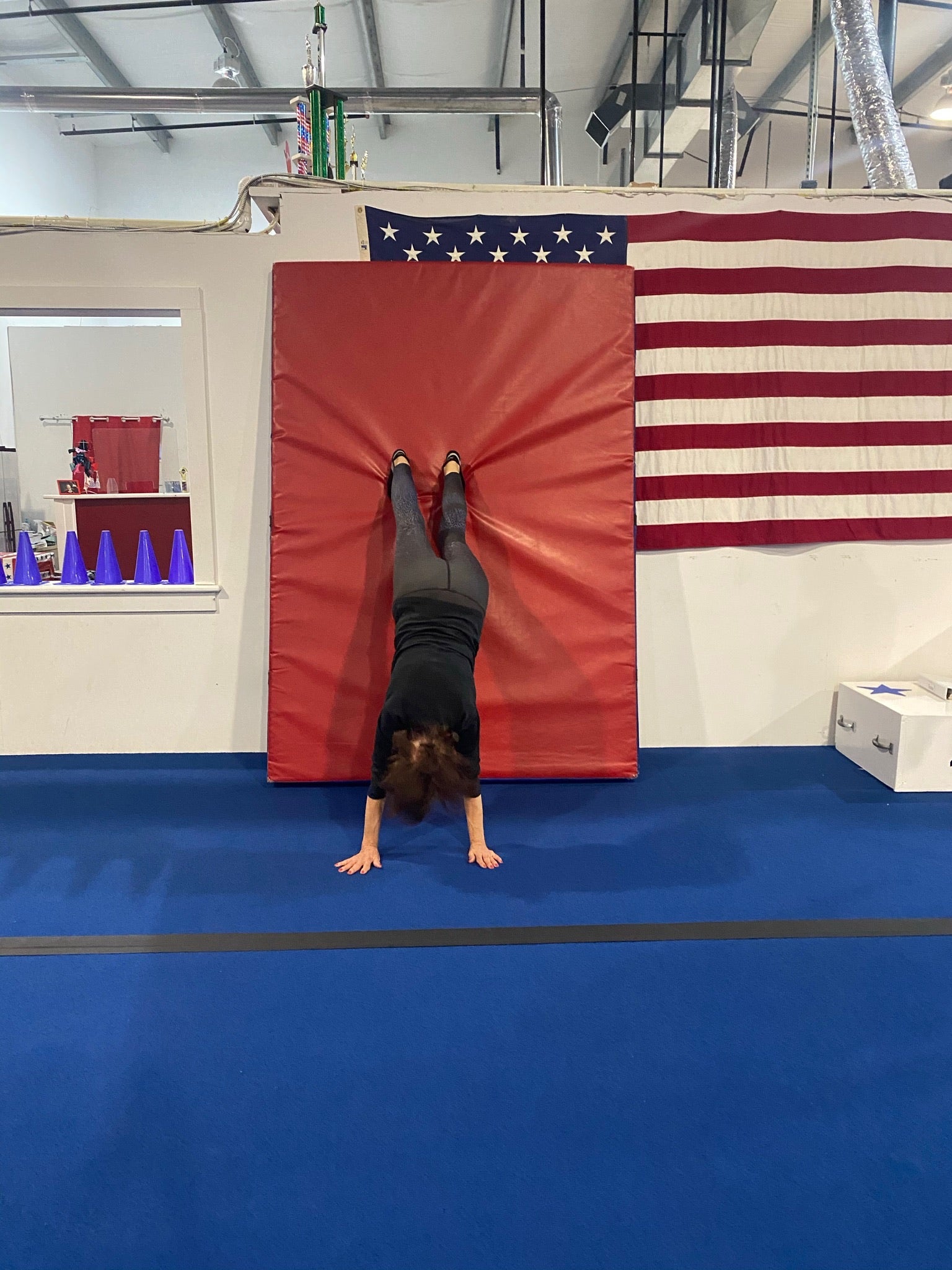 Lori's mother, Lynne, doing a handstand against a mat at an adult gymnastics class